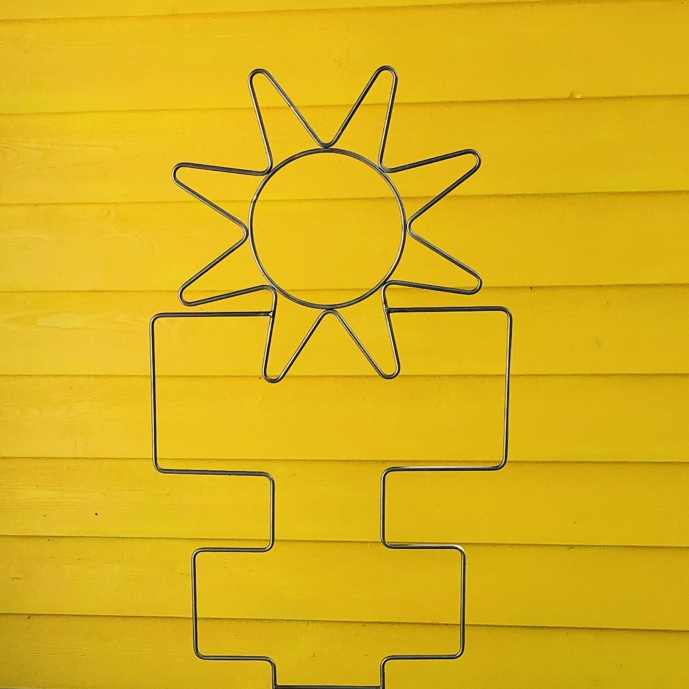 Eine Sonne aus Rohr vor einer gelben Wand
